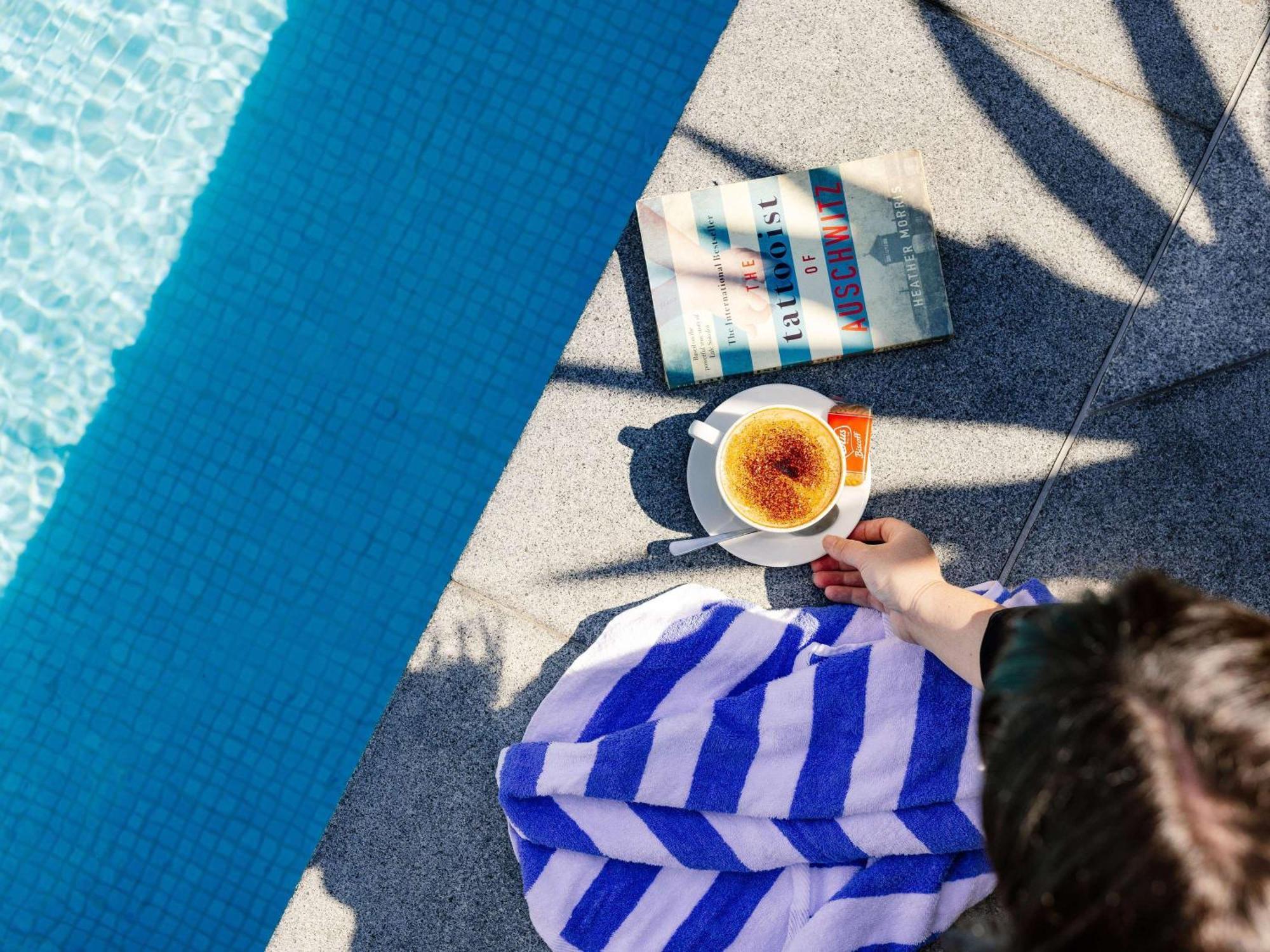 풀먼 브리즈번 공항 호텔 외부 사진 A woman reading a book by the pool